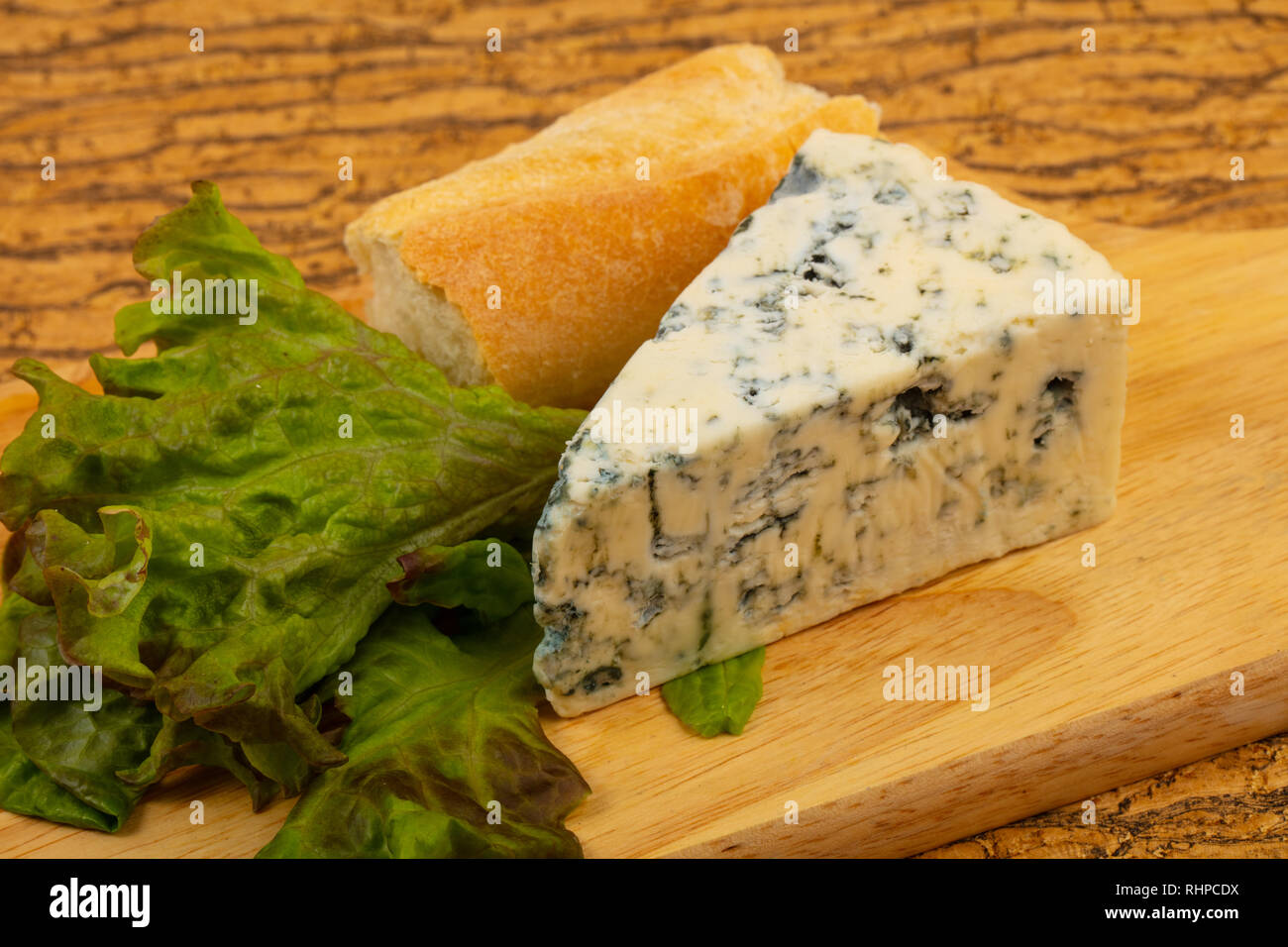 Blue cheese with salad leaves over board Stock Photo Alamy