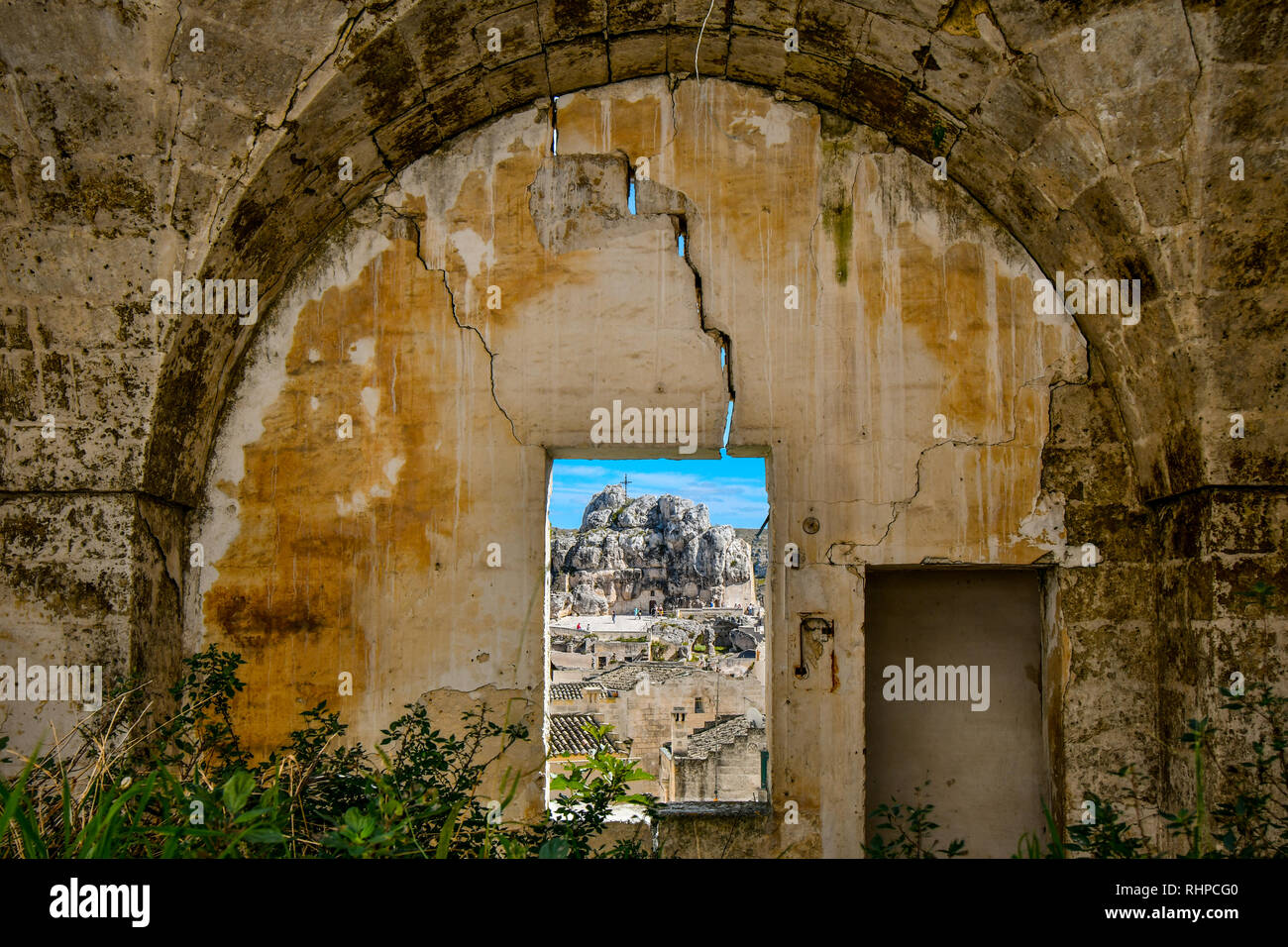 View through a window in a medieval, cracked stone wall of the ancient Madonna de Idris rock church and the Sassi of Matera, Italy Stock Photo