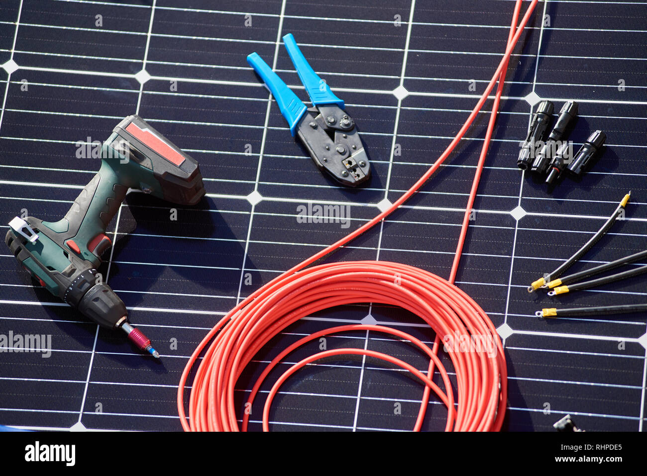 Close-up view of different details and instruments for installing and connecting solar photovoltaic system. Objects laying on blue solar panel Stock Photo
