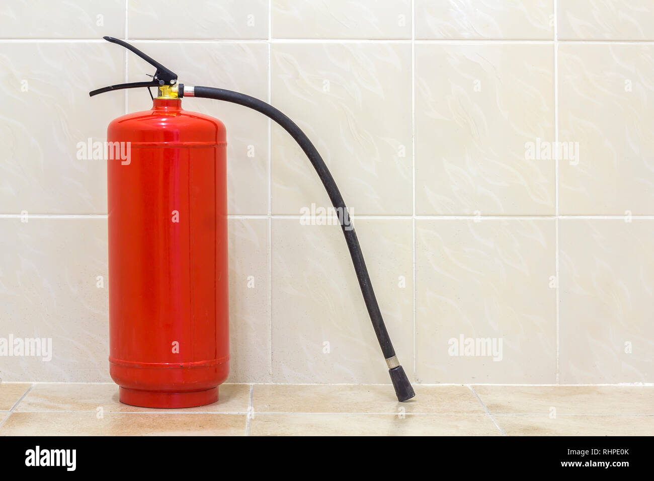 Fire extinguisher bright red isolated on white light tiles walls and floor copy space background. Danger and safety, fire protection concept. Stock Photo