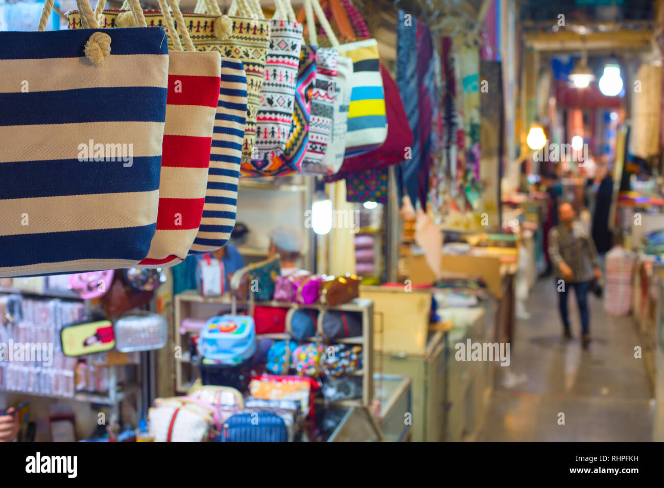 Grand Bazaar market in Tehran, rows of colorful textile crafts shops, bags in foreground, Iran Stock Photo