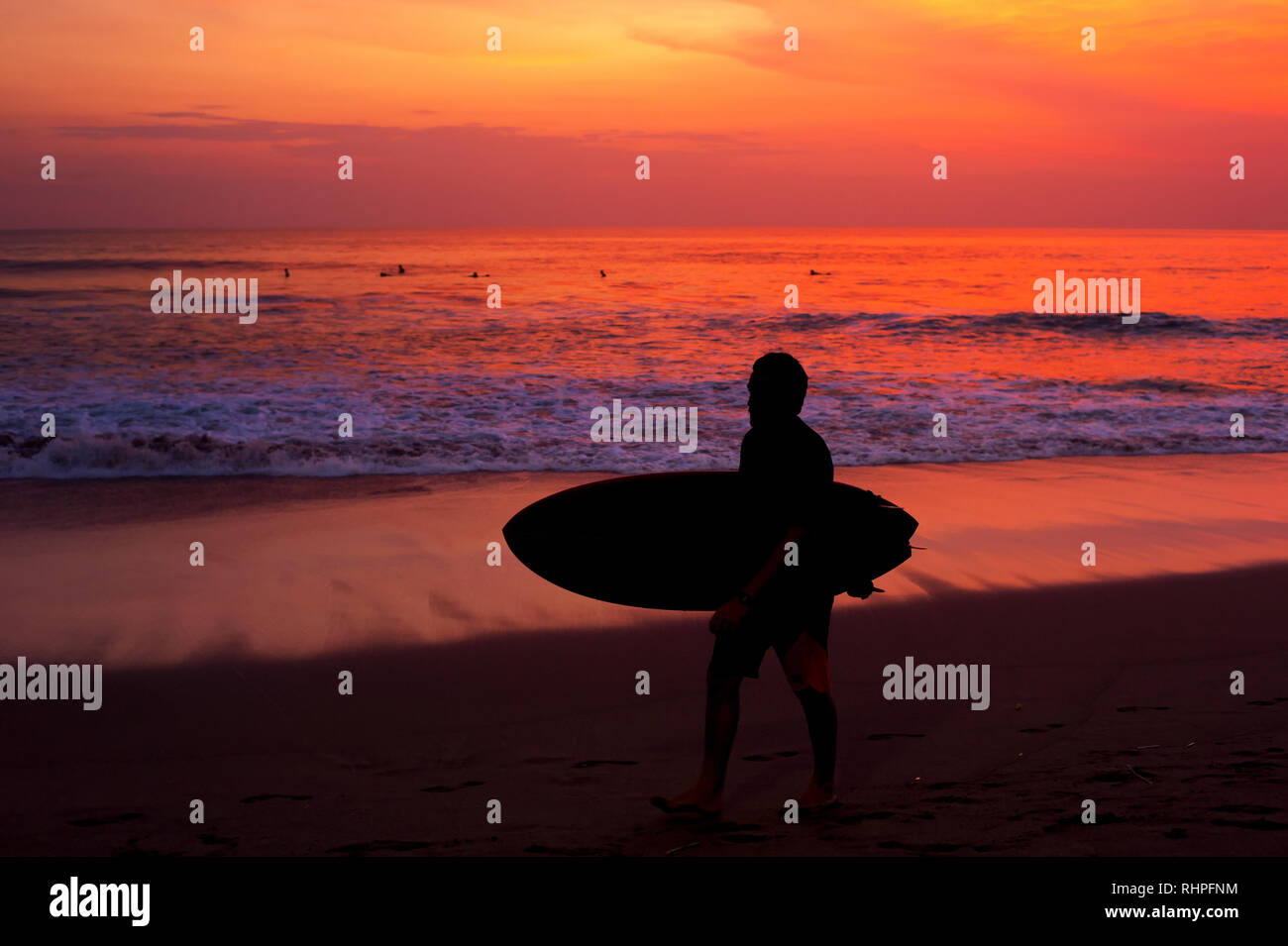 Surfer with surfboard walking by the ocean beach. Bali island