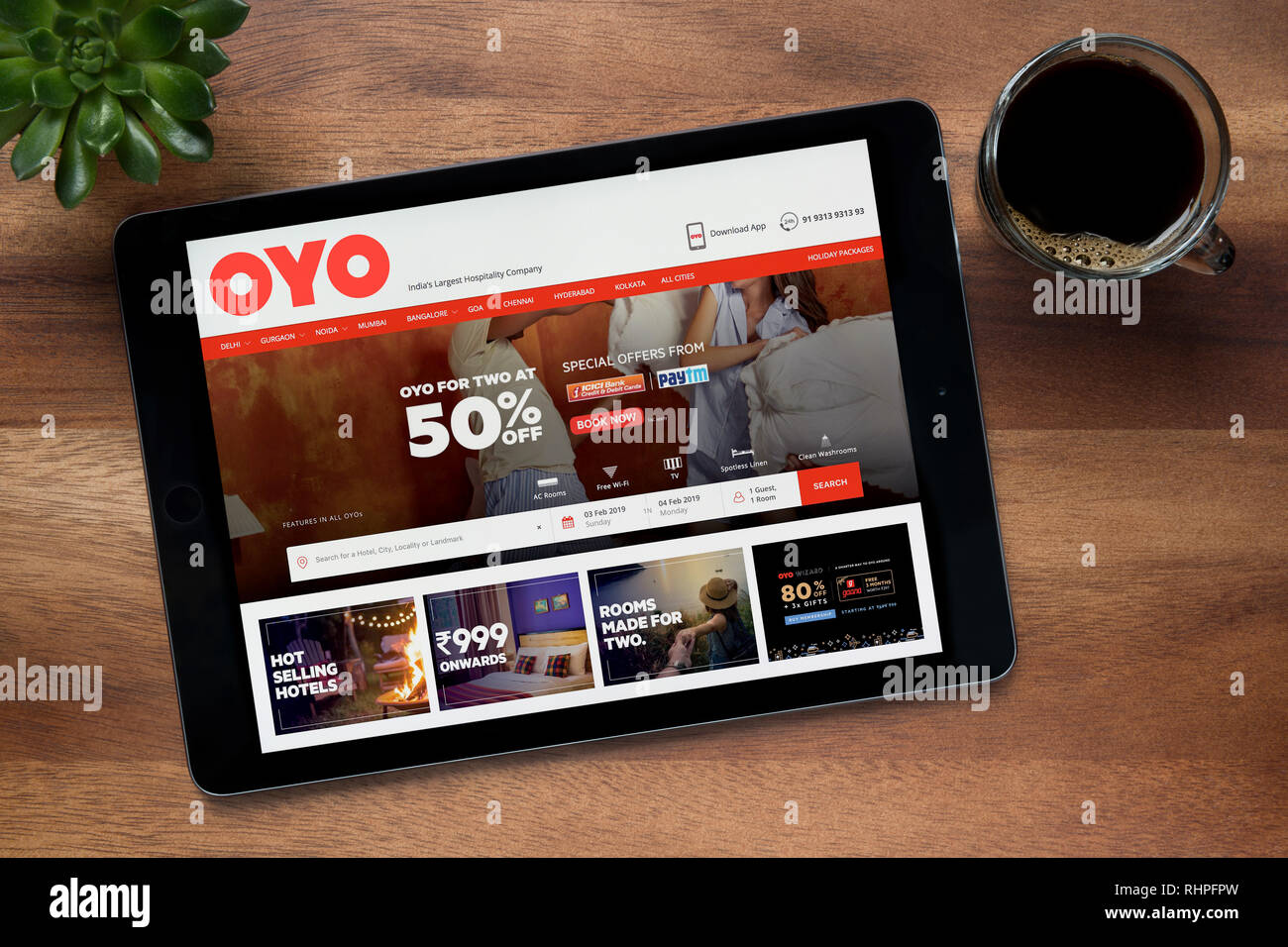 The website of OYO Rooms is seen on an iPad tablet, on a wooden table along with an espresso coffee and a house plant (Editorial use only). Stock Photo