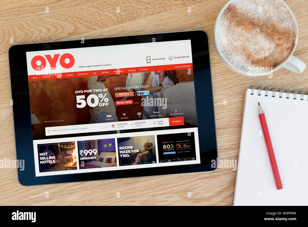 The OYO Rooms website features on an iPad tablet device which rests on a wooden table beside a notepad (Editorial use only). Stock Photo
