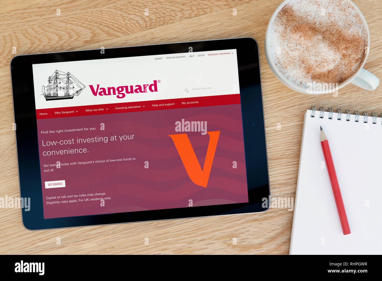 The Vanguard website features on an iPad tablet device which rests on a wooden table beside a notepad (Editorial use only). Stock Photo