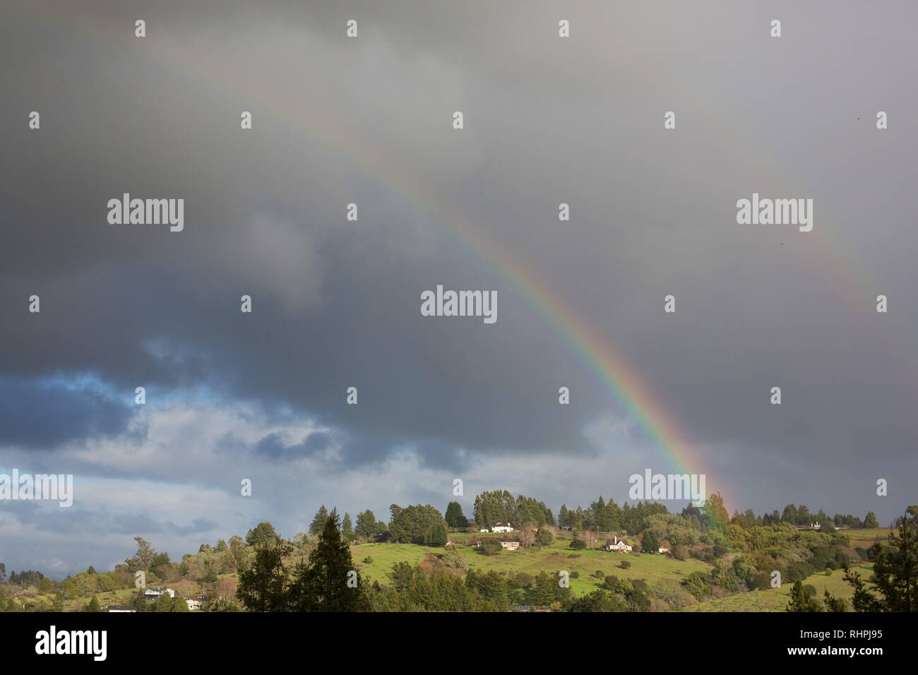 A rainbow emerges from a dark cloud over rural Sonoma County, near Sebastopol, Caifornia, USA. Stock Photo