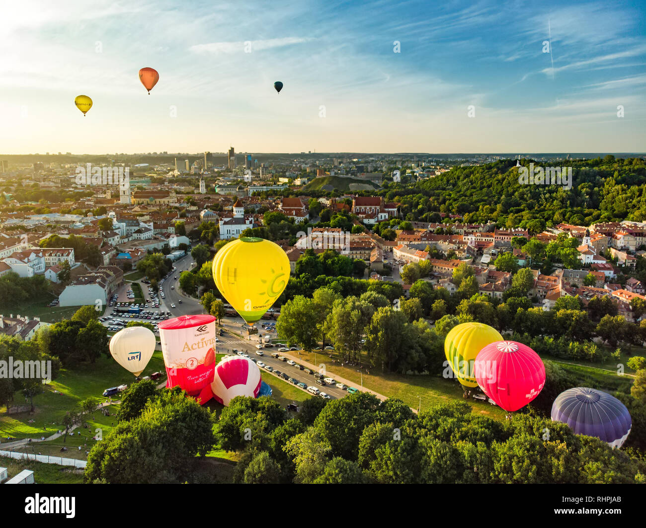 VILNIUS, LITHUANIA - AUGUST 15, 2018: Colorful hot air balloons taking off in Old town of Vilnius city on sunny summer evening. Lots of people watchin Stock Photo
