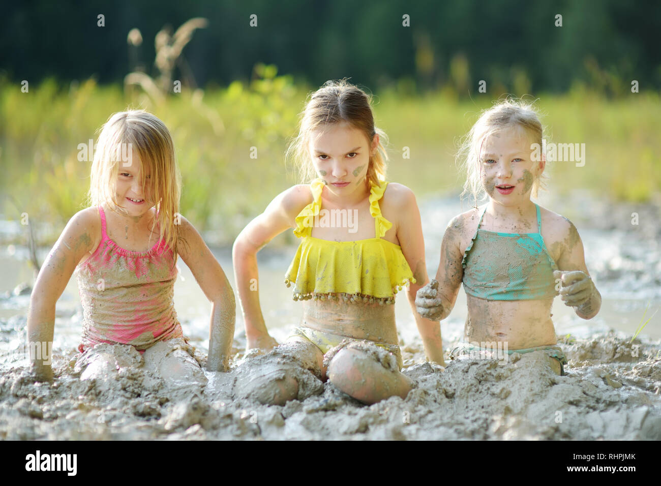 Three young sisters taking healing mud baths on lake Gela near Vilnius ...