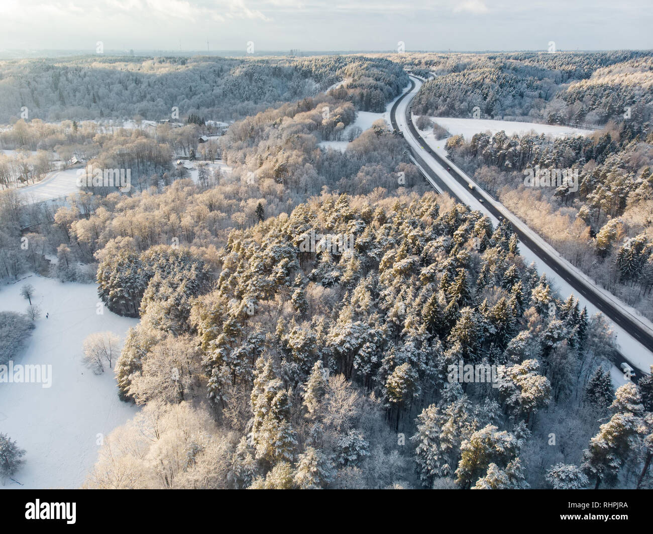 Beautiful aerial view of snow covered pine forests and a road winding ...
