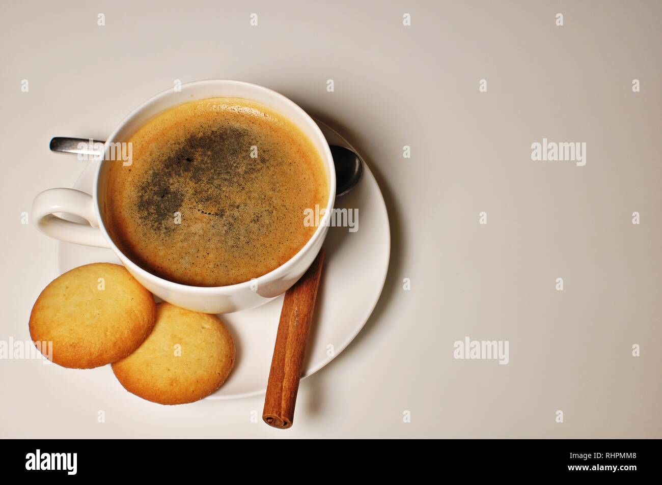 Hot cup of coffee with biscuits and cinnamon stick as decoration. Top table, copy text Stock Photo
