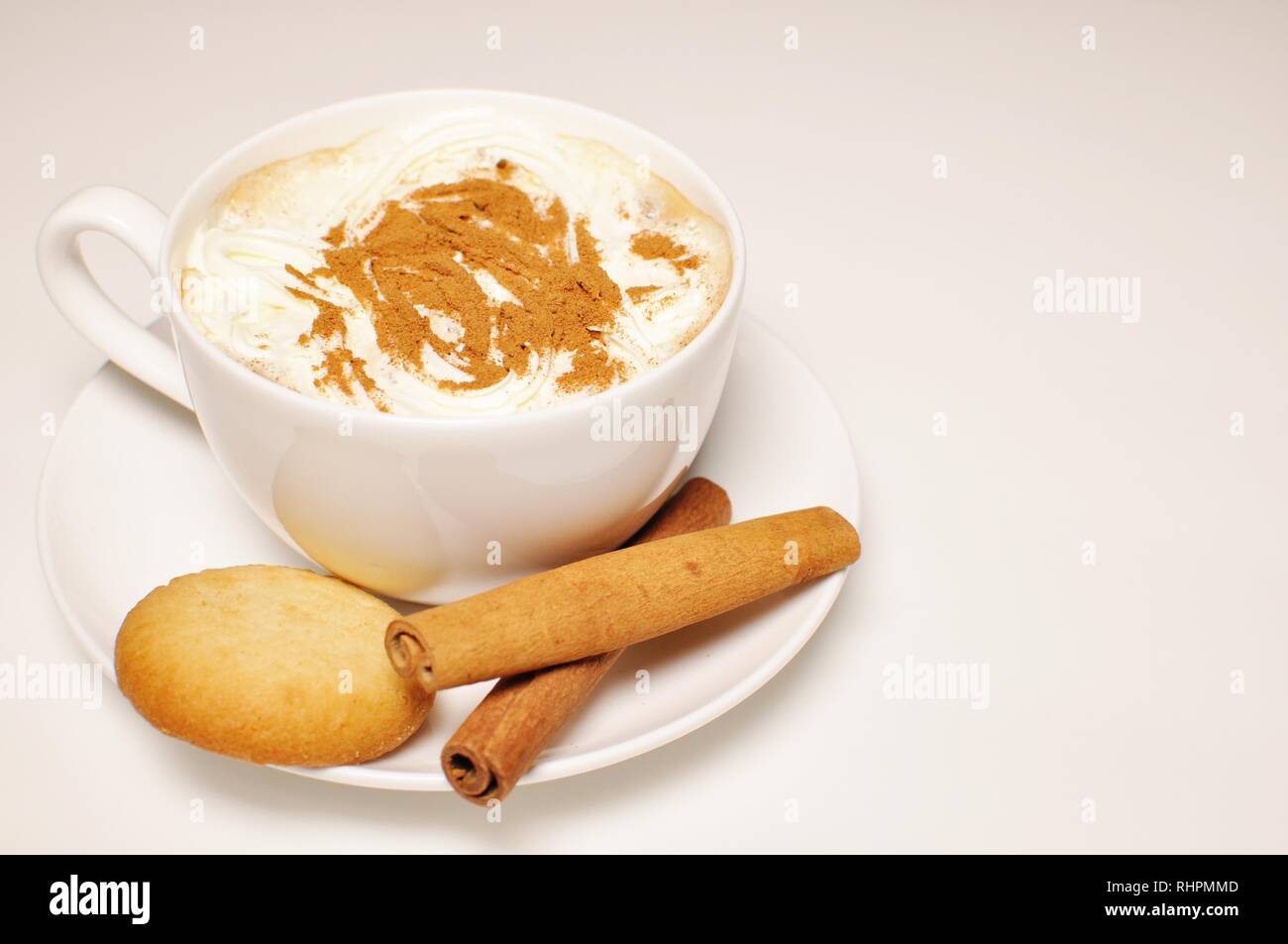 Close up of a hot cup of cappuccino with biscuits and cinnamon stick as decoration. Top side view, copy space Stock Photo