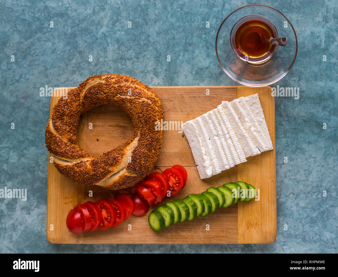 Typical Turkish breakfast of simit, tomatoes, cucumber and cheese, with Turkish tea, served in a glass. Stock Photo