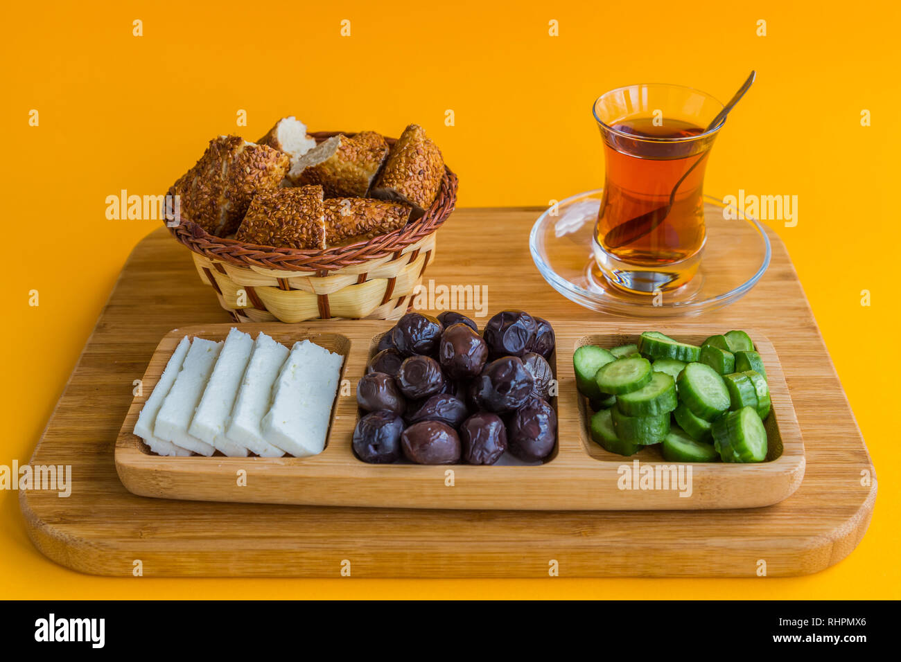 Typical Turkish breakfast of simit, cucumber, olives, and cheese, with Turkish tea, served in a glass. Stock Photo