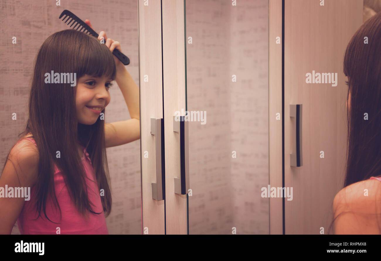 Cute smiling girl combs her long hair in front of the mirror Stock ...
