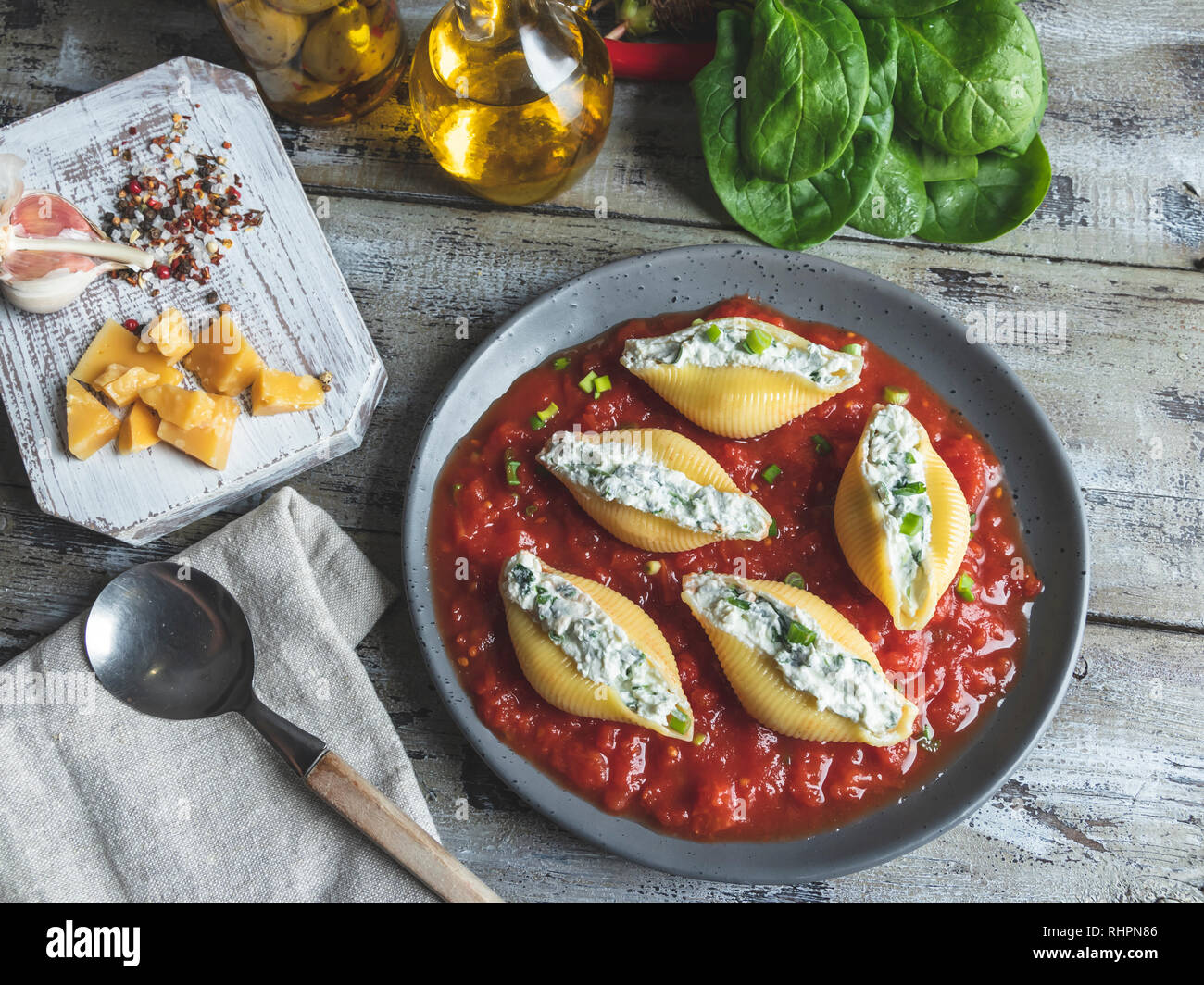 cooked pasta conchiglioni stuffed spinach and cheese, tomato sauce on plate Stock Photo