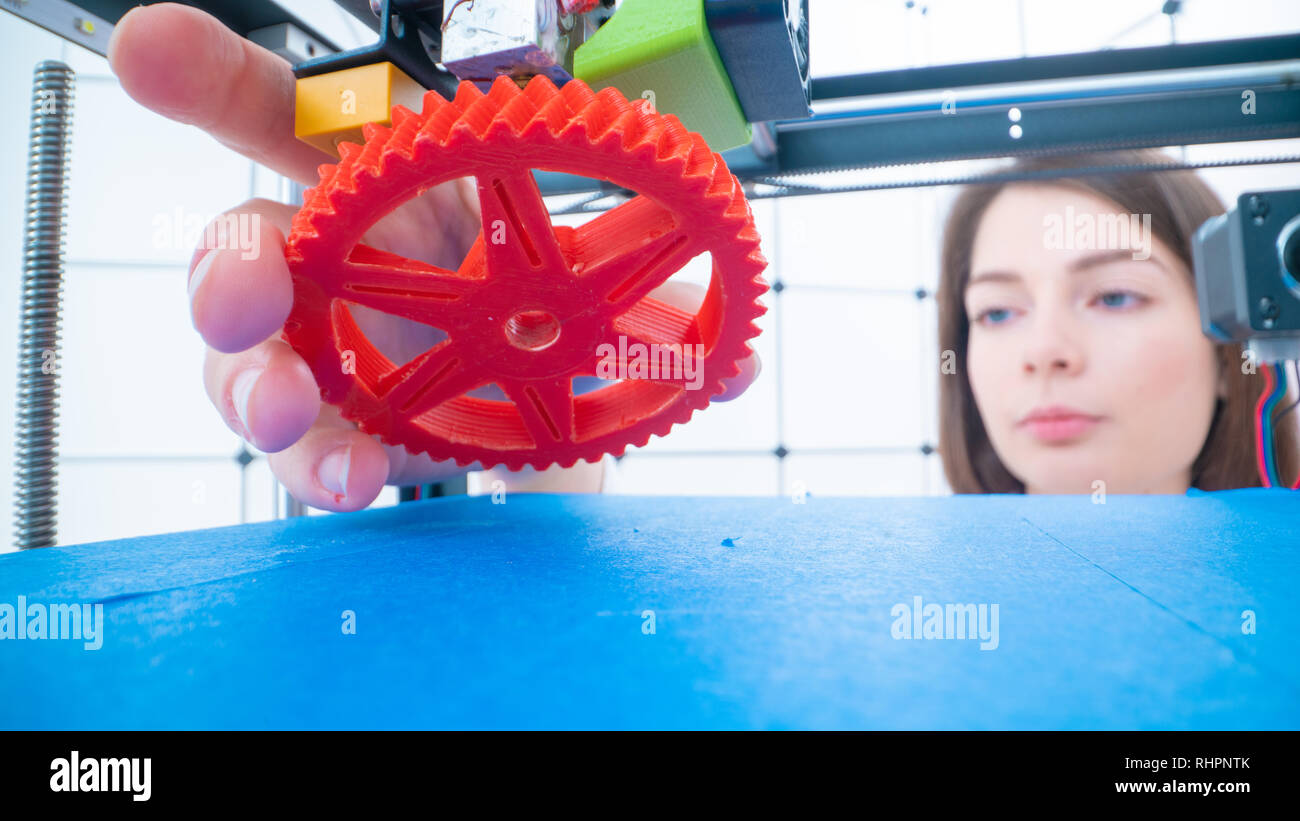 Young women designer in 3d printing lab. Girl takes the finished detail from 3D printer Stock Photo