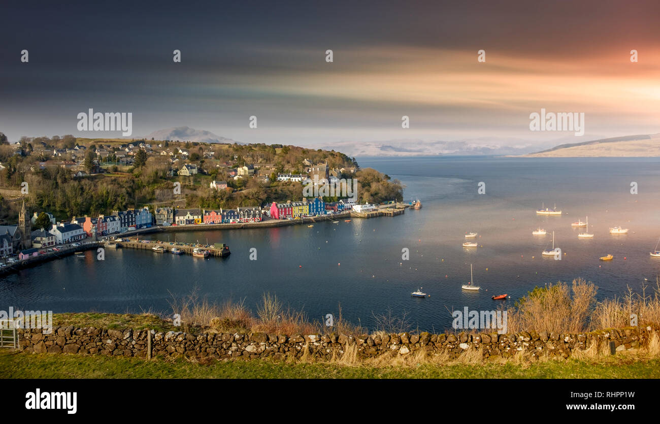 Beautiful sunrise over Tobermory Bay on the Isle of Mull. Scotland mainland highland peaks in the background. Stock Photo