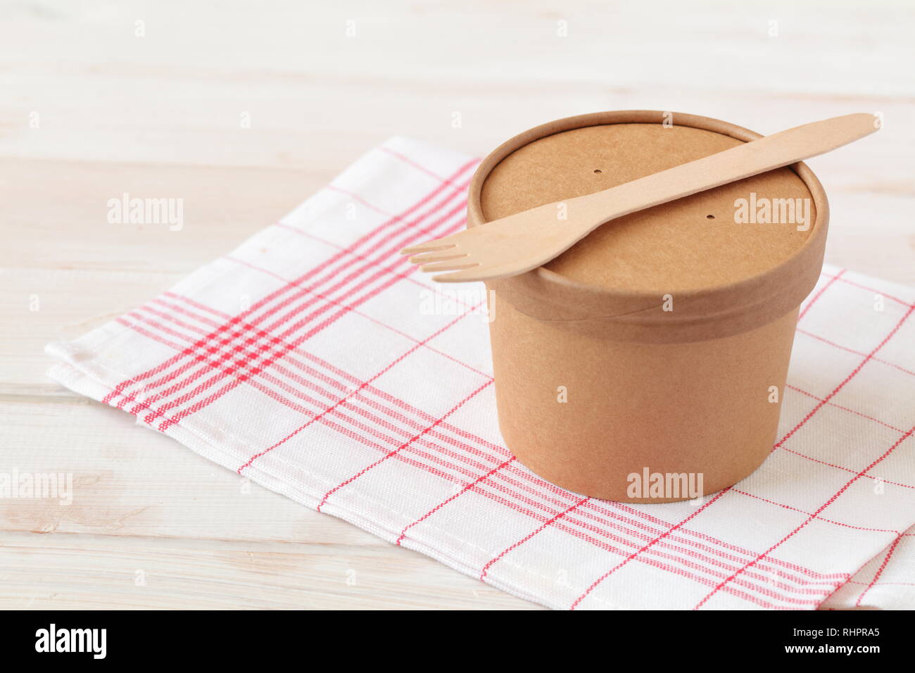 Kraft paper soup bowl with lid and wooden fork on a white table Stock Photo