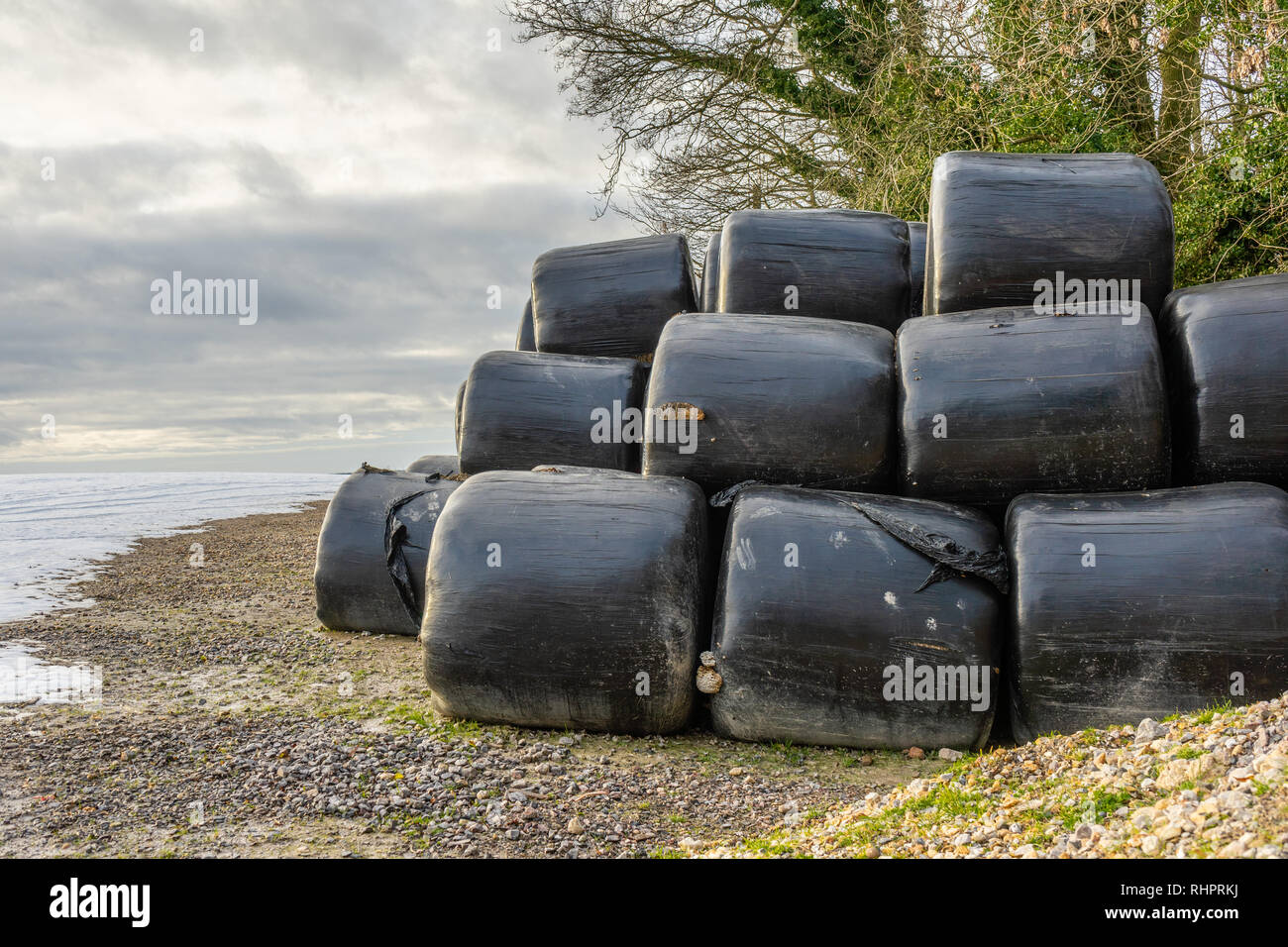 Stacked hay bales during winter covered in black plastic for protection Stock Photo
