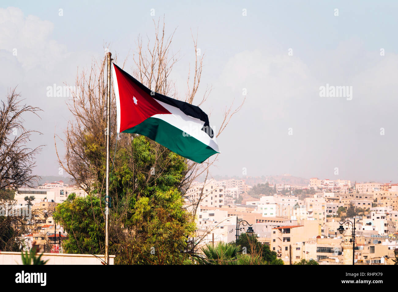 tricolor flag of Jordan on the background of the old poor of the city and blue sky Stock Photo