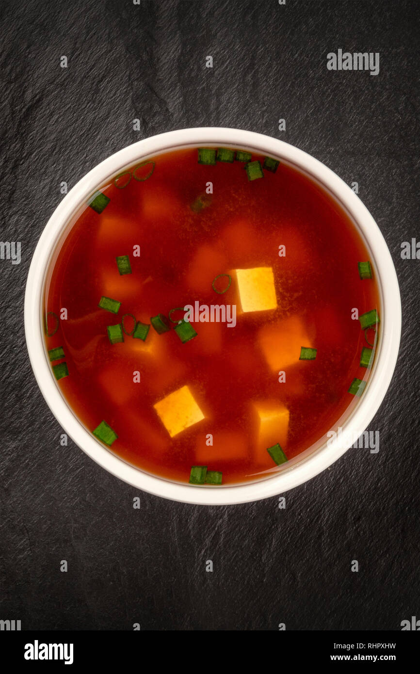 An overhead photo of a bowl of miso soup with tofu and scallions on a