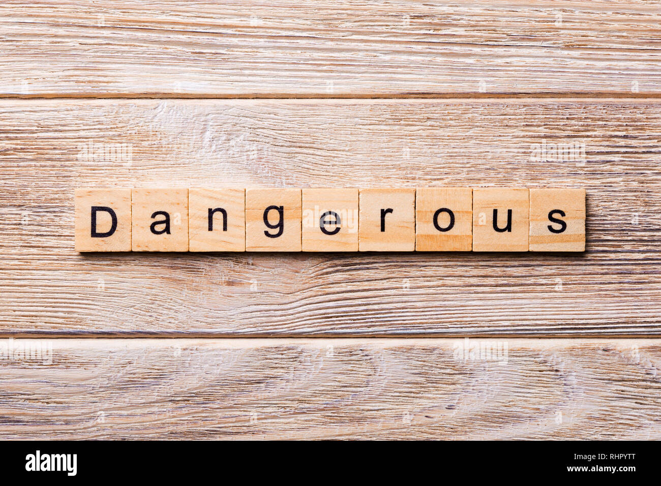 dangerous word written on wood block. dangerous text on wooden table for your desing, concept. Stock Photo