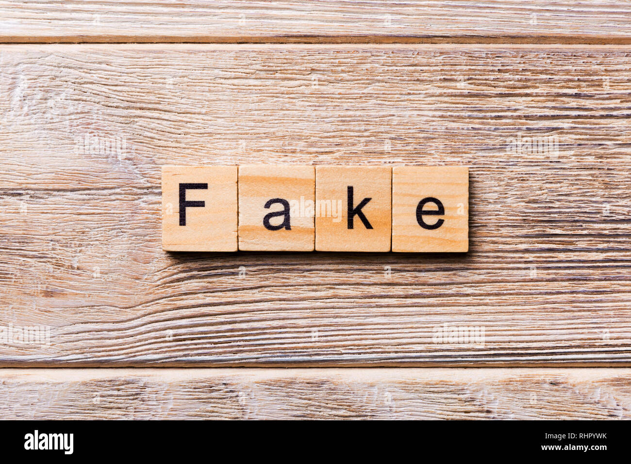 Fake word written on wood block. Fake text on wooden table for your