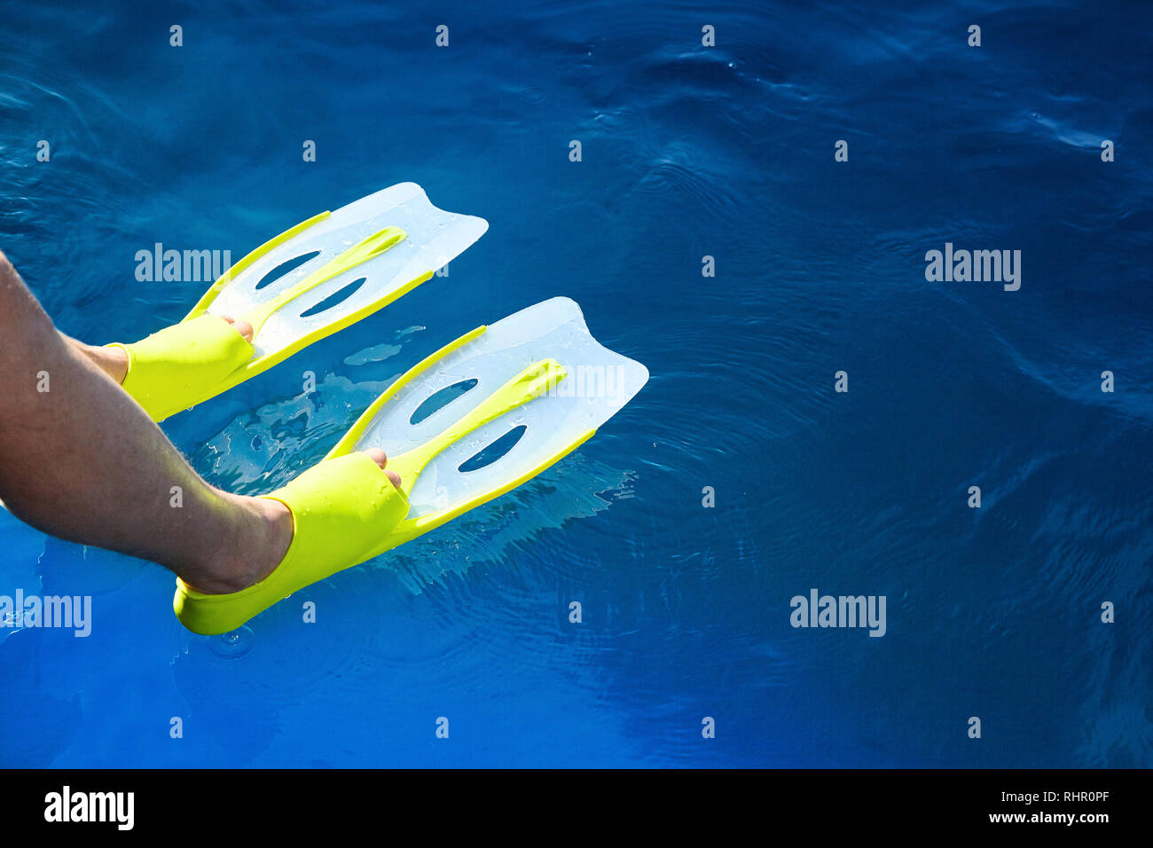 Feet with flippers on the blue sea while snorkeling. Active diving