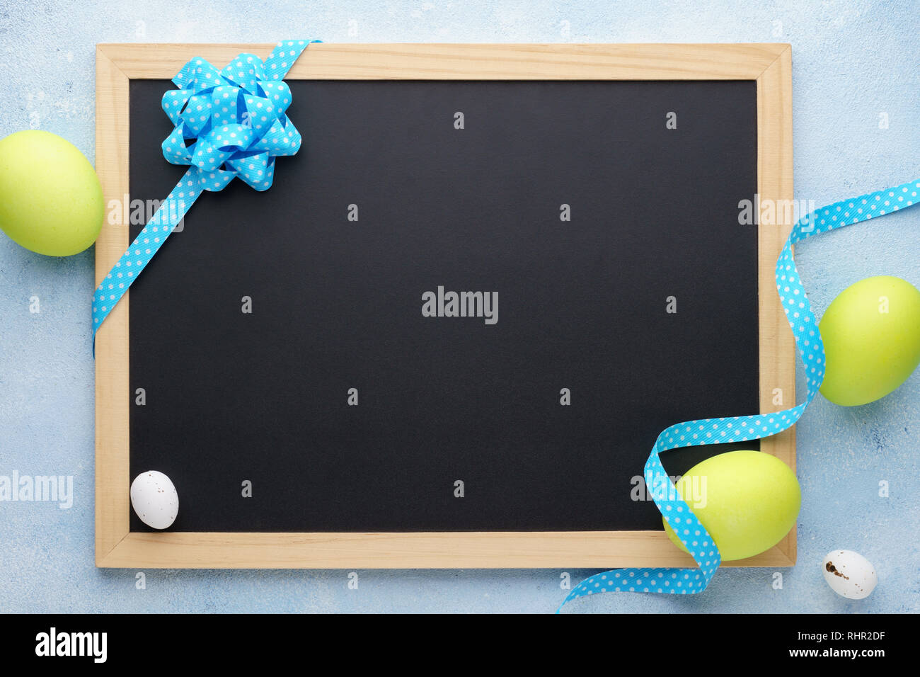 Easter frame with painted green eggs and empty chalkboard. Background with copy space. Stock Photo