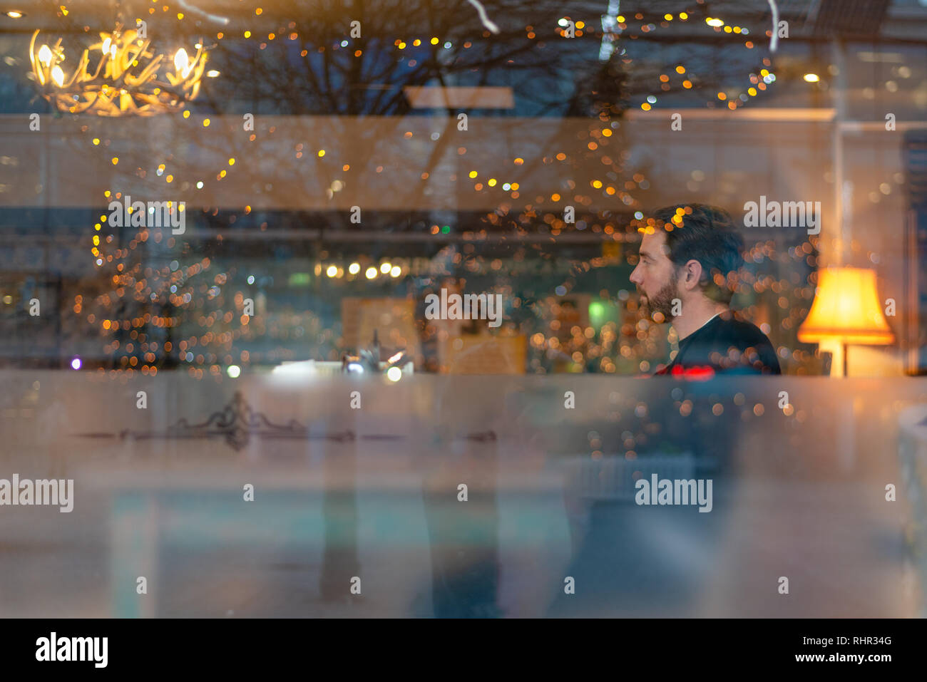 Handsome man with beard in coffee shop with lights reflecting Stock Photo