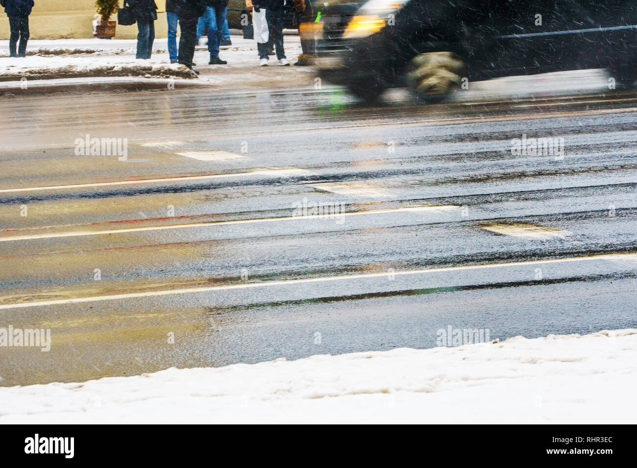 Crosswalk. Slippery wet asphalt city road in winter. Driving cars are
