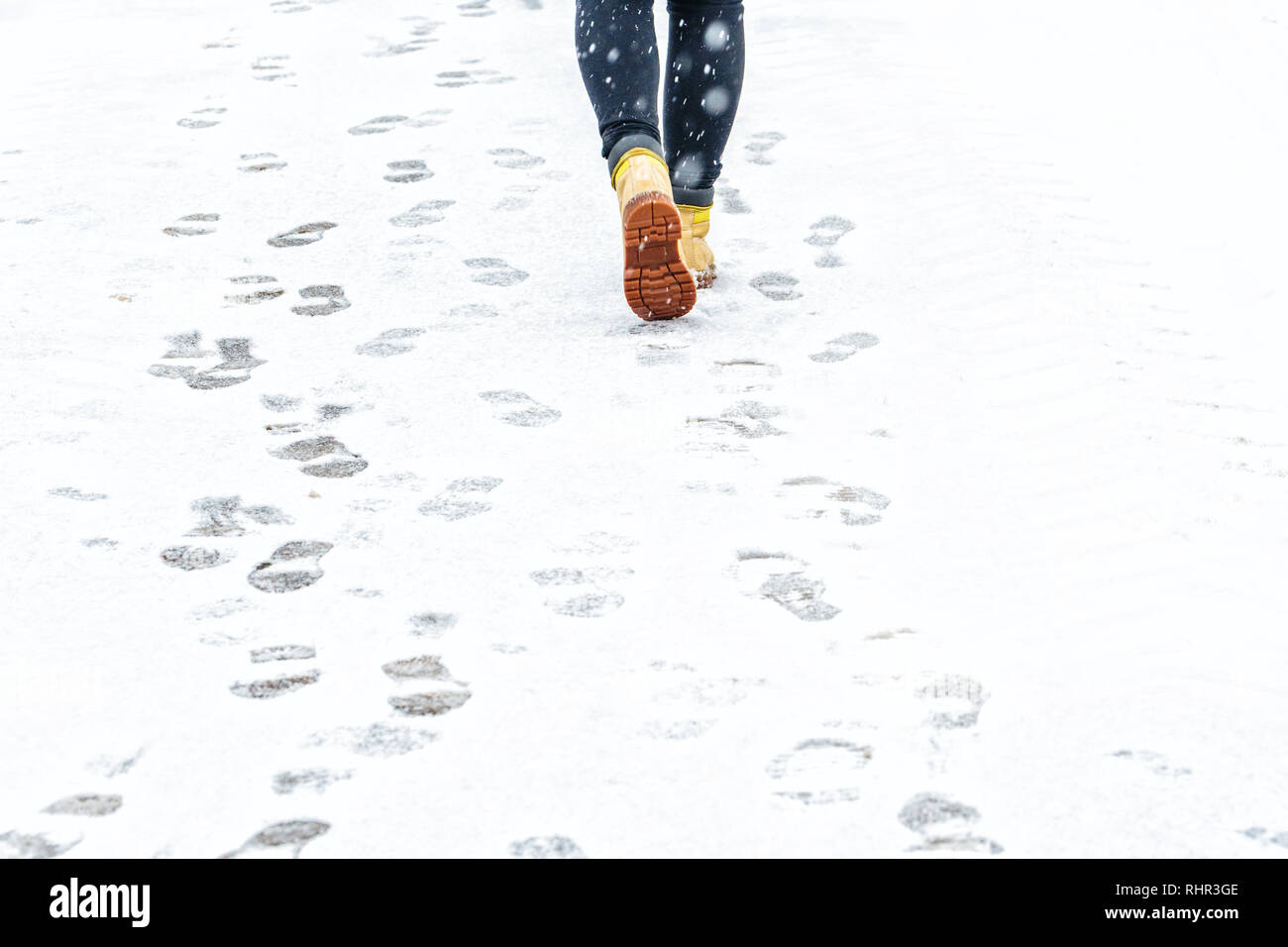 Winter Walk in Yellow Leather Boots. Back view on the feet of a man walking along the icy snowy