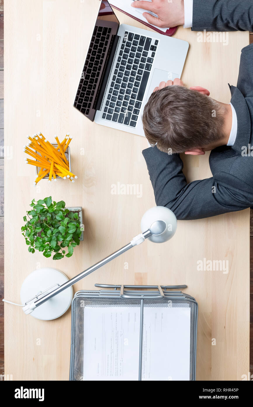 Directly above view of tired businessman lying by laptop at desk in office Stock Photo