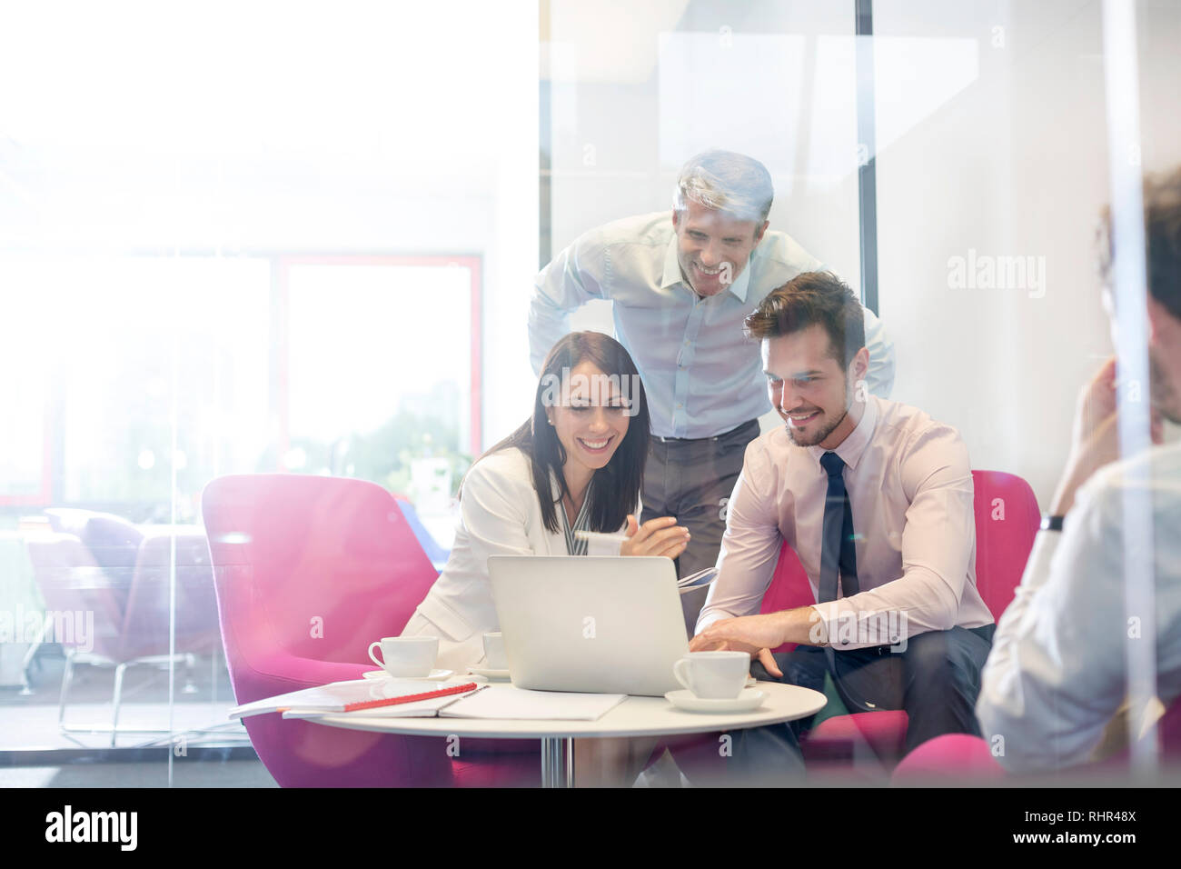 Happy business people discussing over laptop in office meeting Stock ...