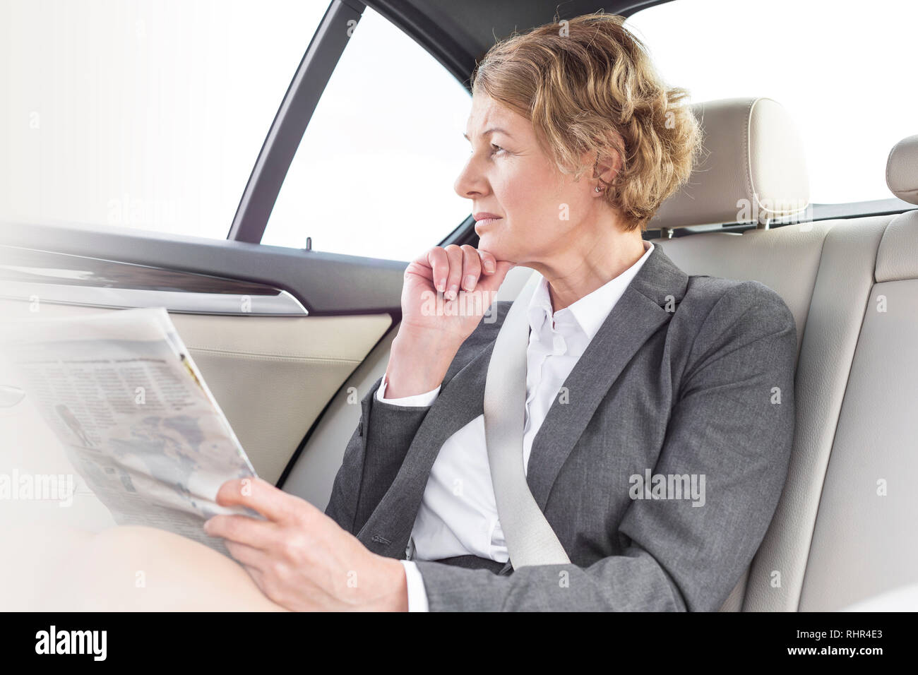 Thoughtful businesswoman with newspaper sitting in car Stock Photo