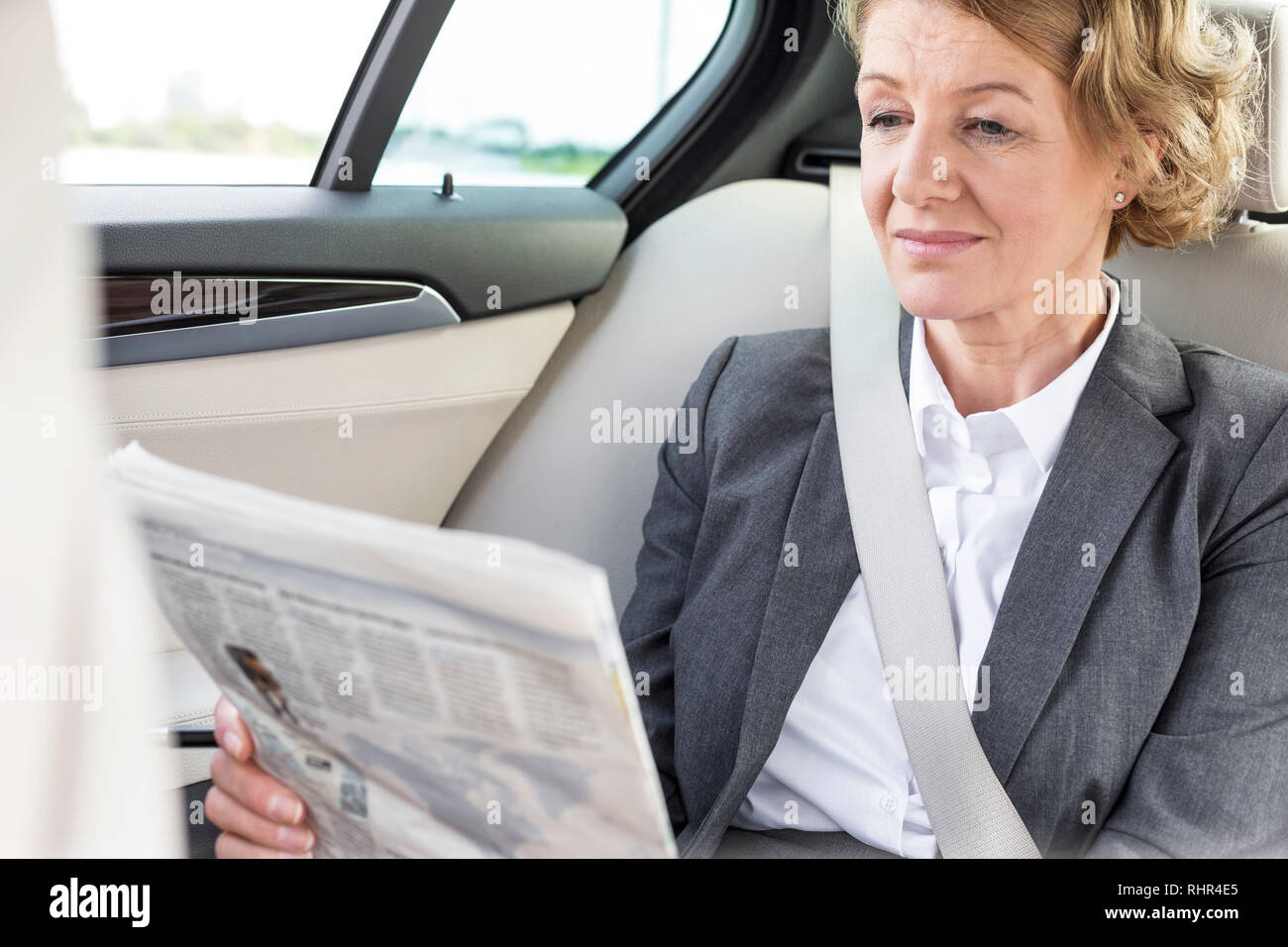 Mature businesswoman reading newspaper while sitting in car Stock Photo