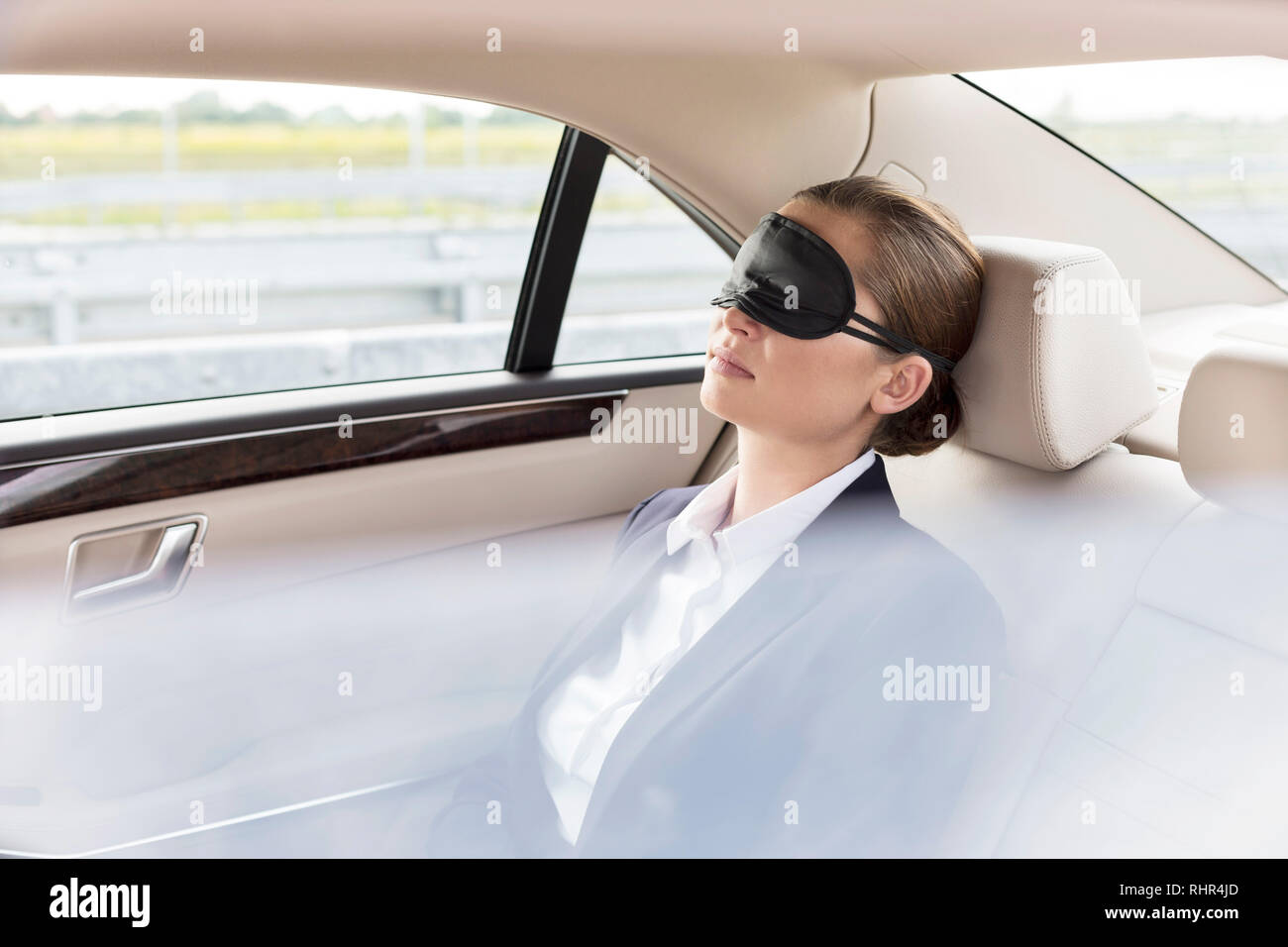 Businesswoman napping with mask in car during travel Stock Photo