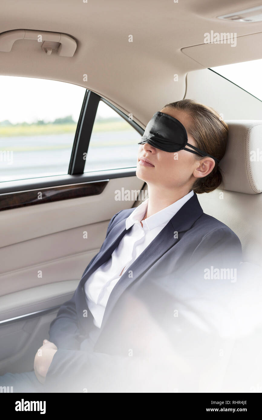 Executive with mask napping in car during travel Stock Photo
