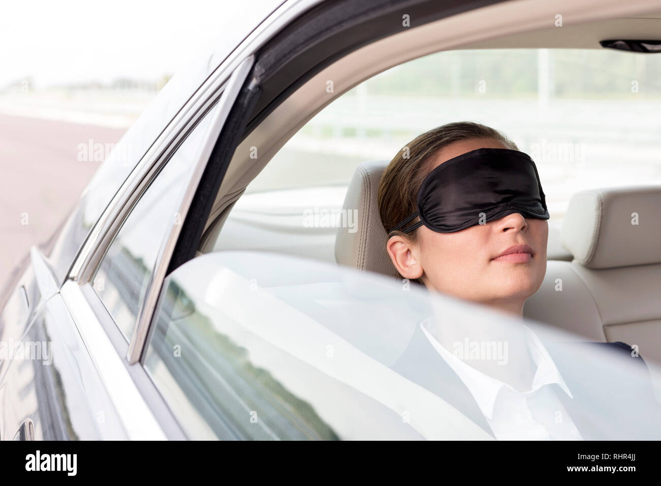 Closeup of businesswoman napping with mask in car Stock Photo