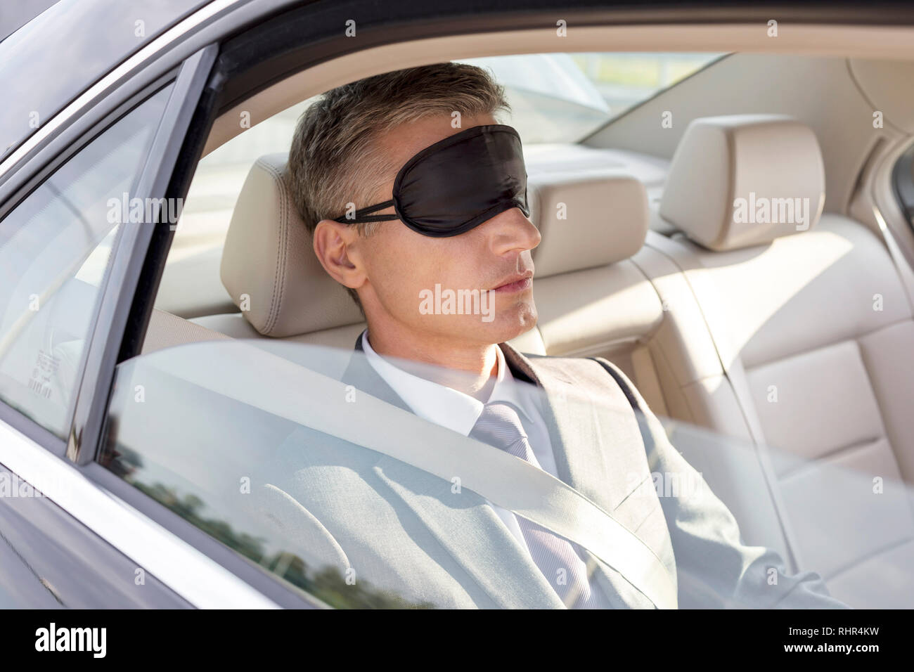 Businessman napping while wearing eye mask in car Stock Photo
