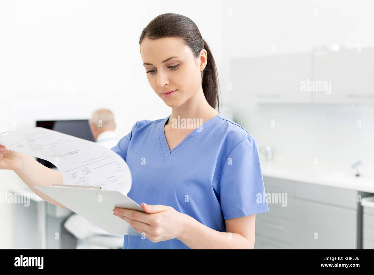 Nurse analyzing medical documents on clipboard at dental clinic Stock Photo