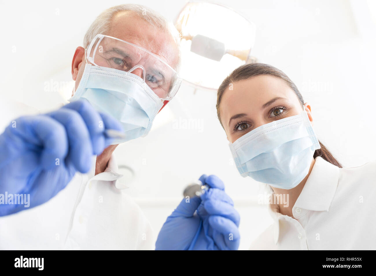 Low angle portrait of male and female dentists wearing masks at dental