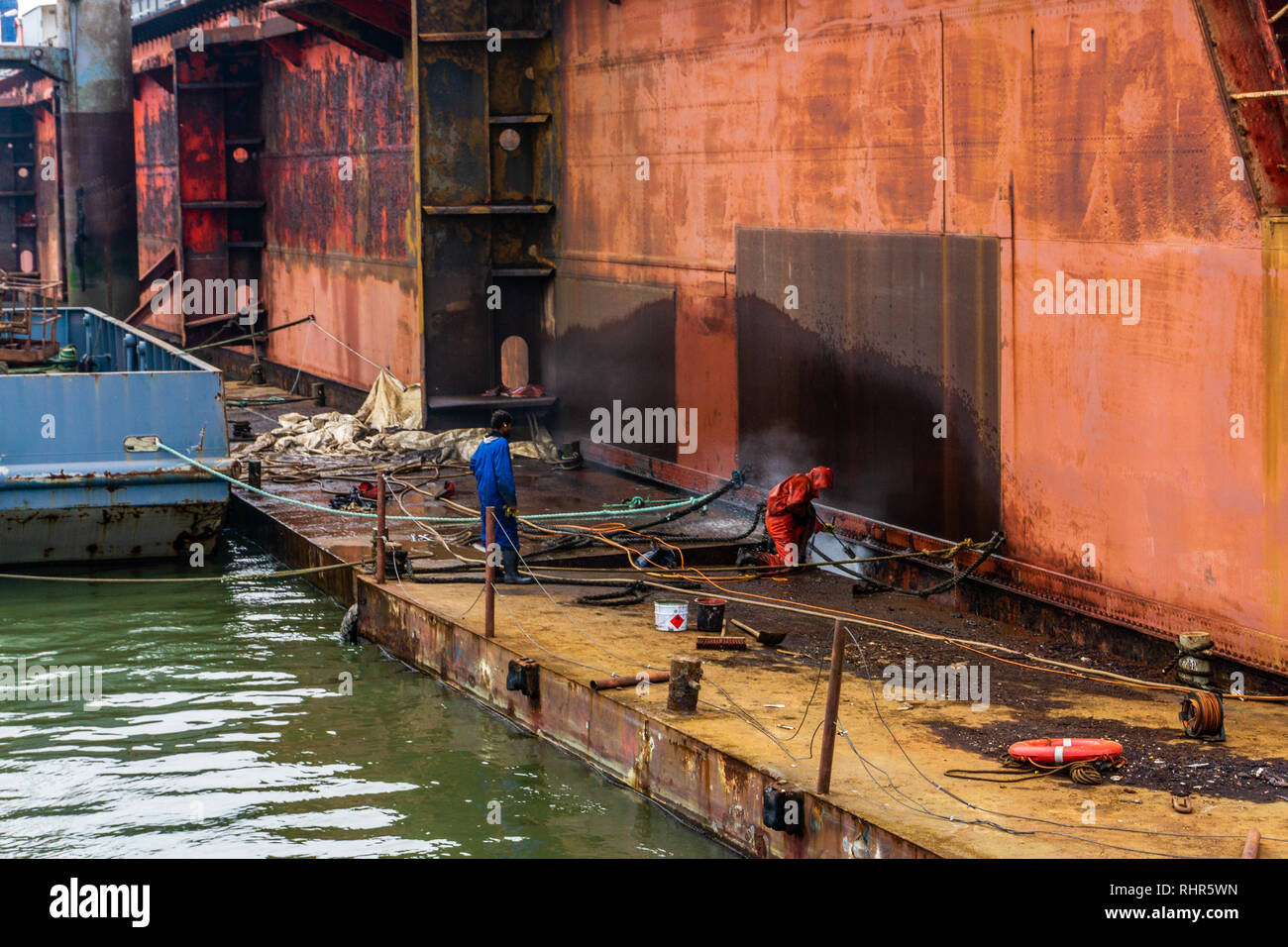 Work in dry dock with water jet cleans the bottom of the ship from sea
