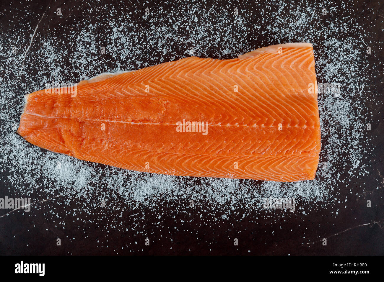 Raw salmon fillet, Salt, ingredients for dry cure marinade on dark