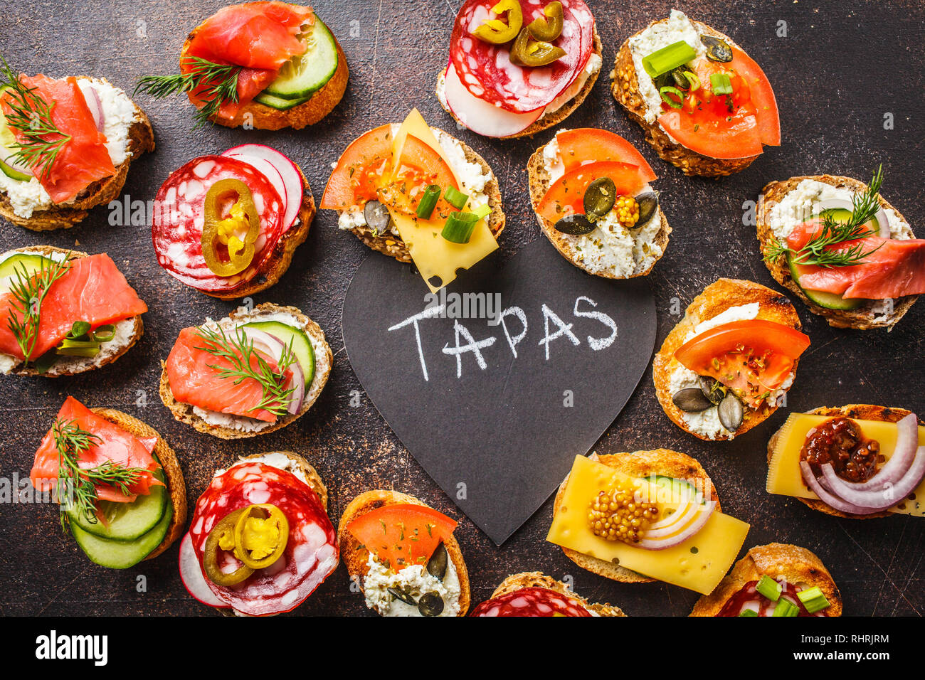 Assorted spanish tapas with fish, sausage, cheese and vegetables. Dark  background, flat lay Stock Photo - Alamy