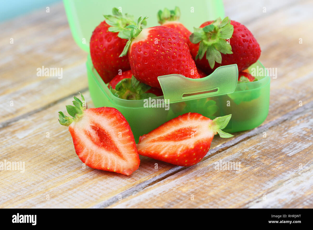 Cross section of a strawberry with box of strawberries in the background Stock Photo