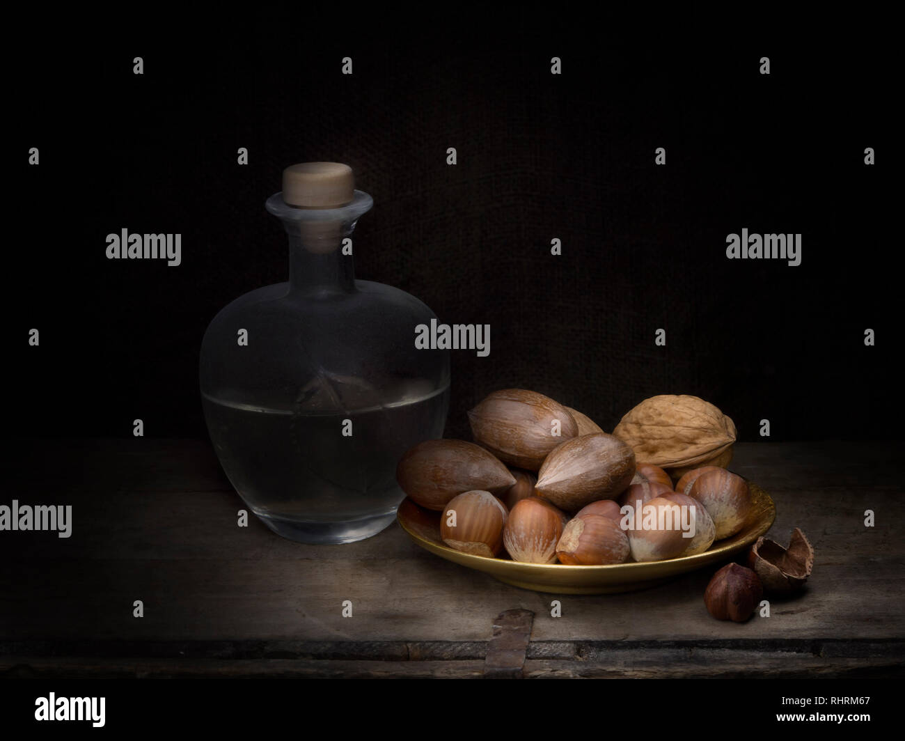 Rustic home made grappa with asorted nuts, still life light painting. Stock Photo