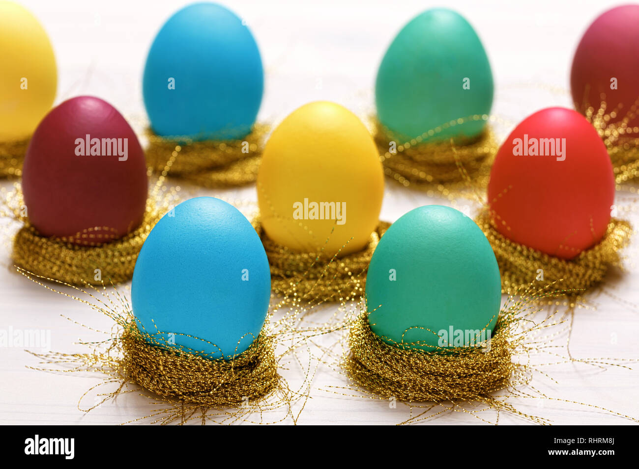 Multi-colored Easter eggs in nests of shiny gold threads Stock Photo