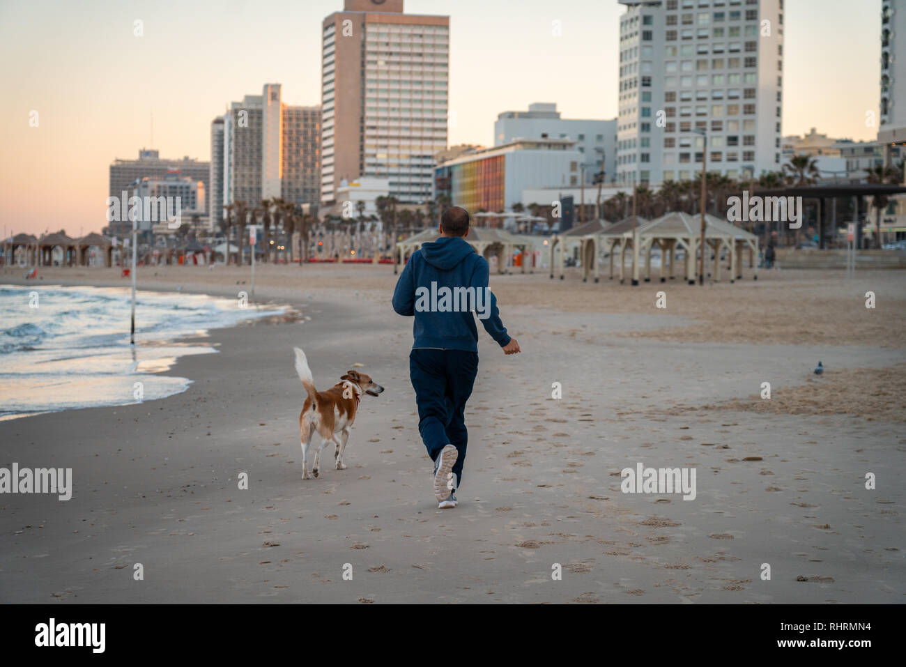 A man runs with his dog on the Tel Aviv beach Stock Photo