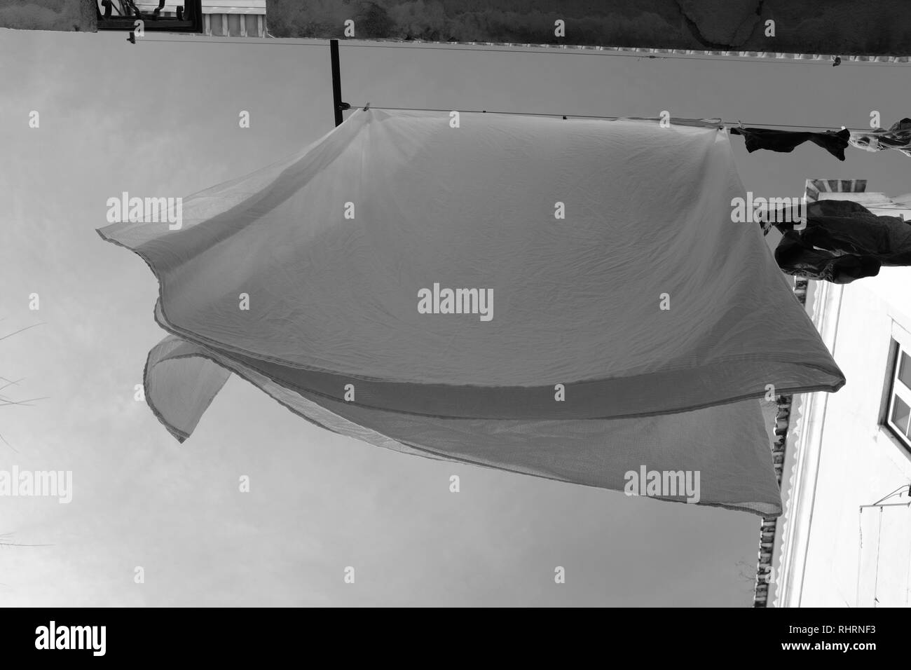 Pure white sheets hanging out to dry on a windy day on a washing line Stock Photo